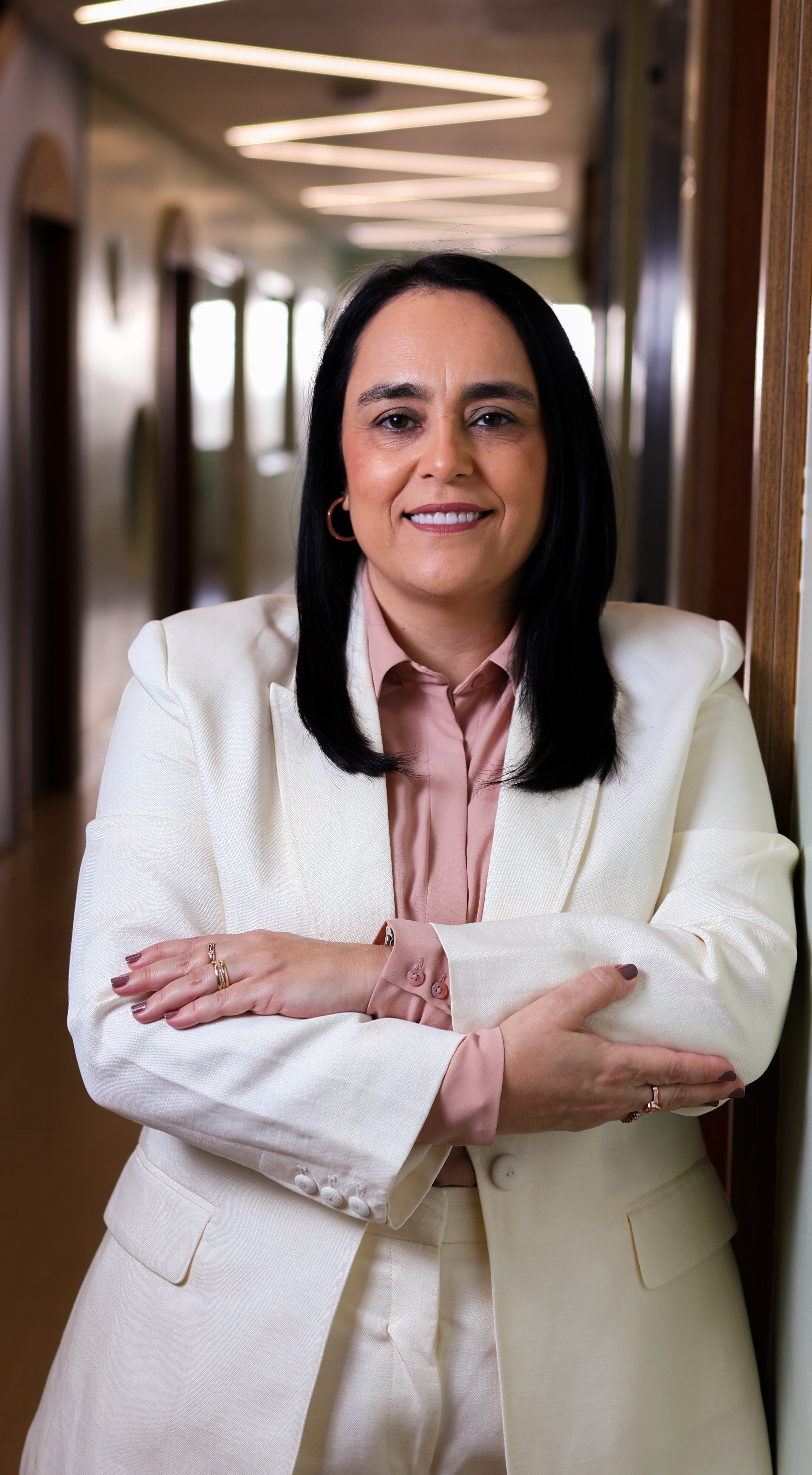 Patrícia Bastos em um corredor, de braços cruzados