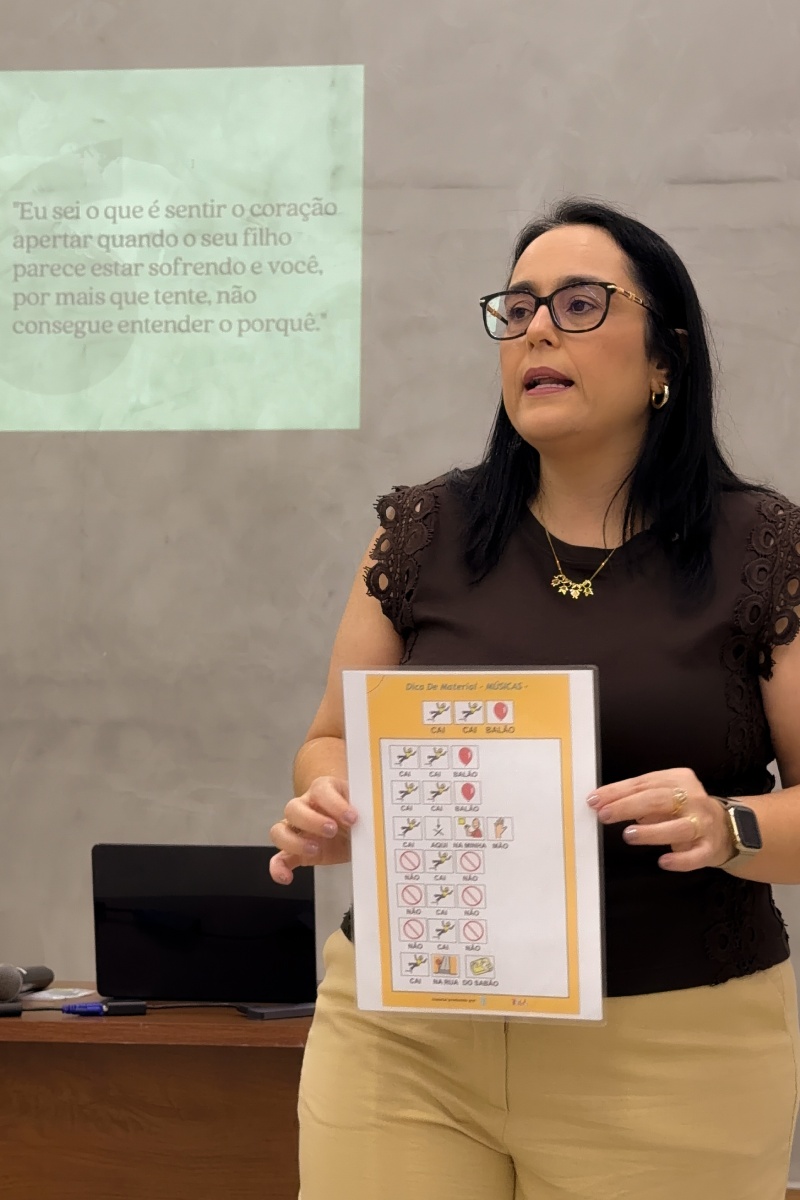 Patrícia Bastos apresentando uma prancha de comunicação alternativa durante uma palestra