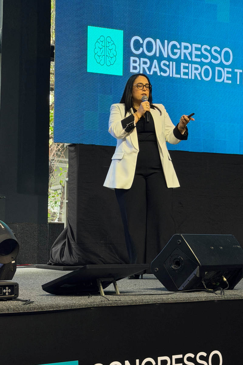Patrícia Bastos no palco do Congresso Brasileiro de TDAH, com o nome do evento no telão