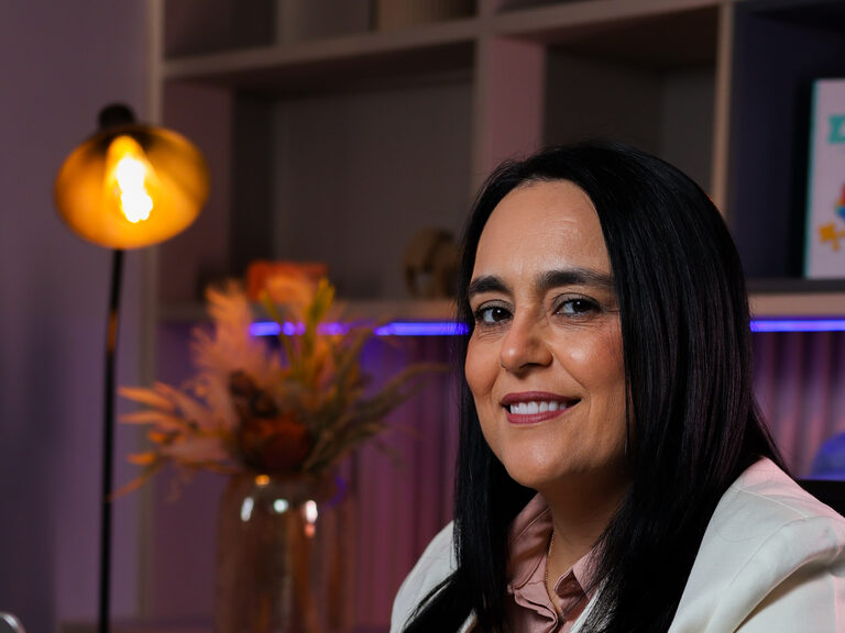 Patrícia Bastos à mesa de trabalho, com livros ao lado