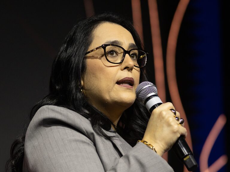 Patrícia Bastos falando ao microfone durante palestra